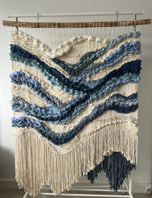 Vertical wall tapestry with cream textured background and flowing blue river design