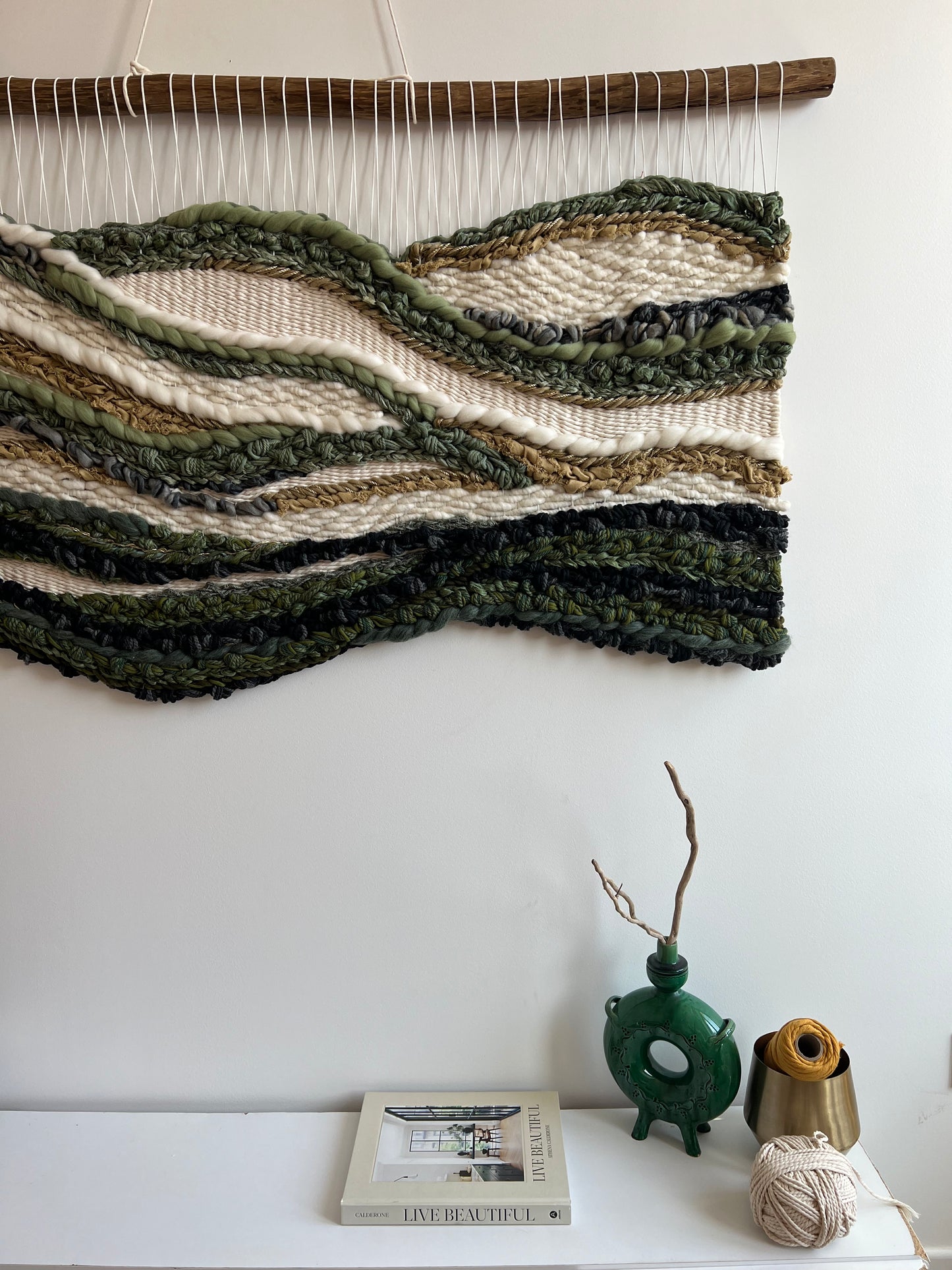 Textured fibers and dark green accents in the wool wall hanging, close-up shot