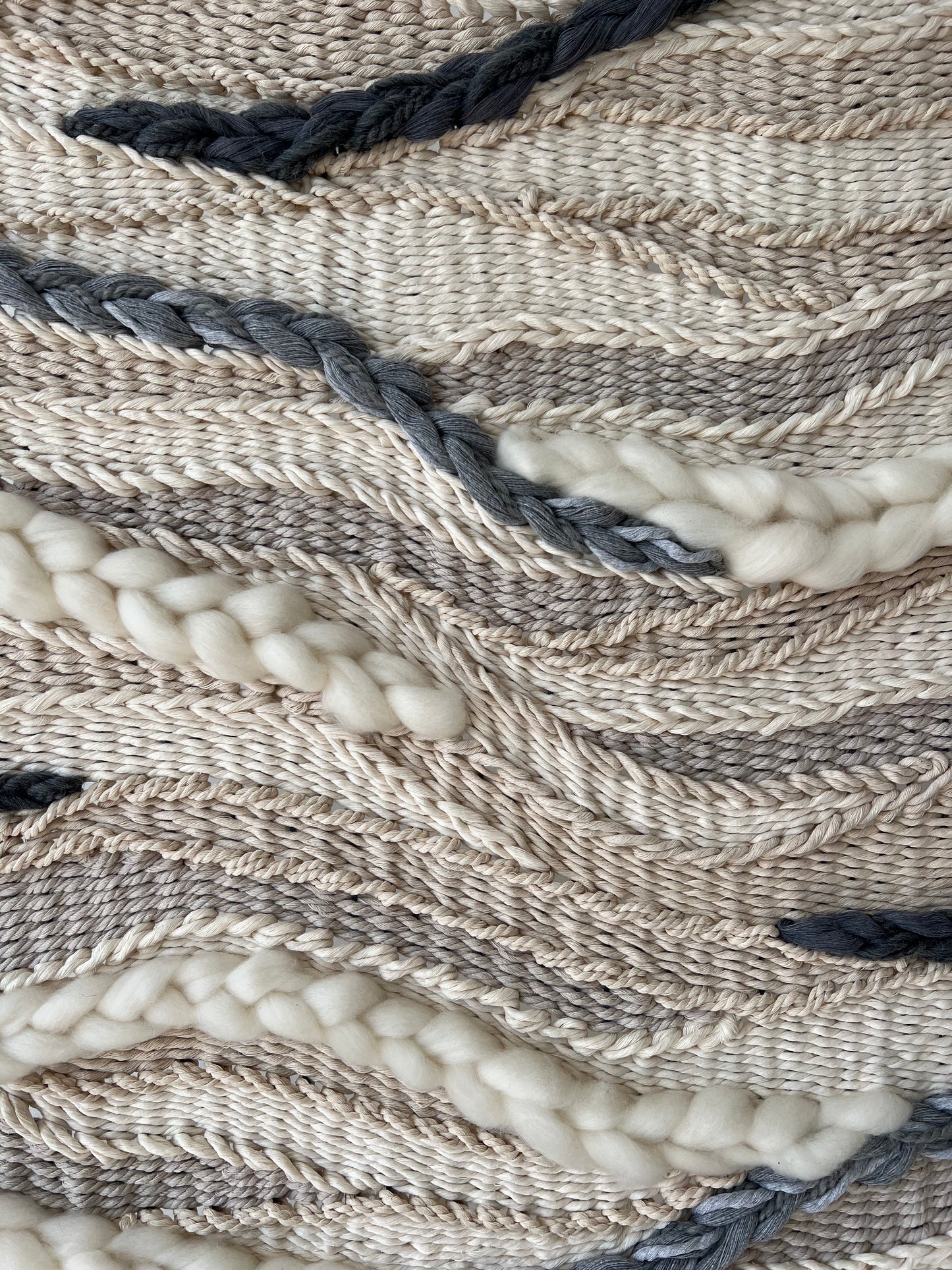 Close-up of the “Stone River” tapestry showing soft cream and gray wool textures