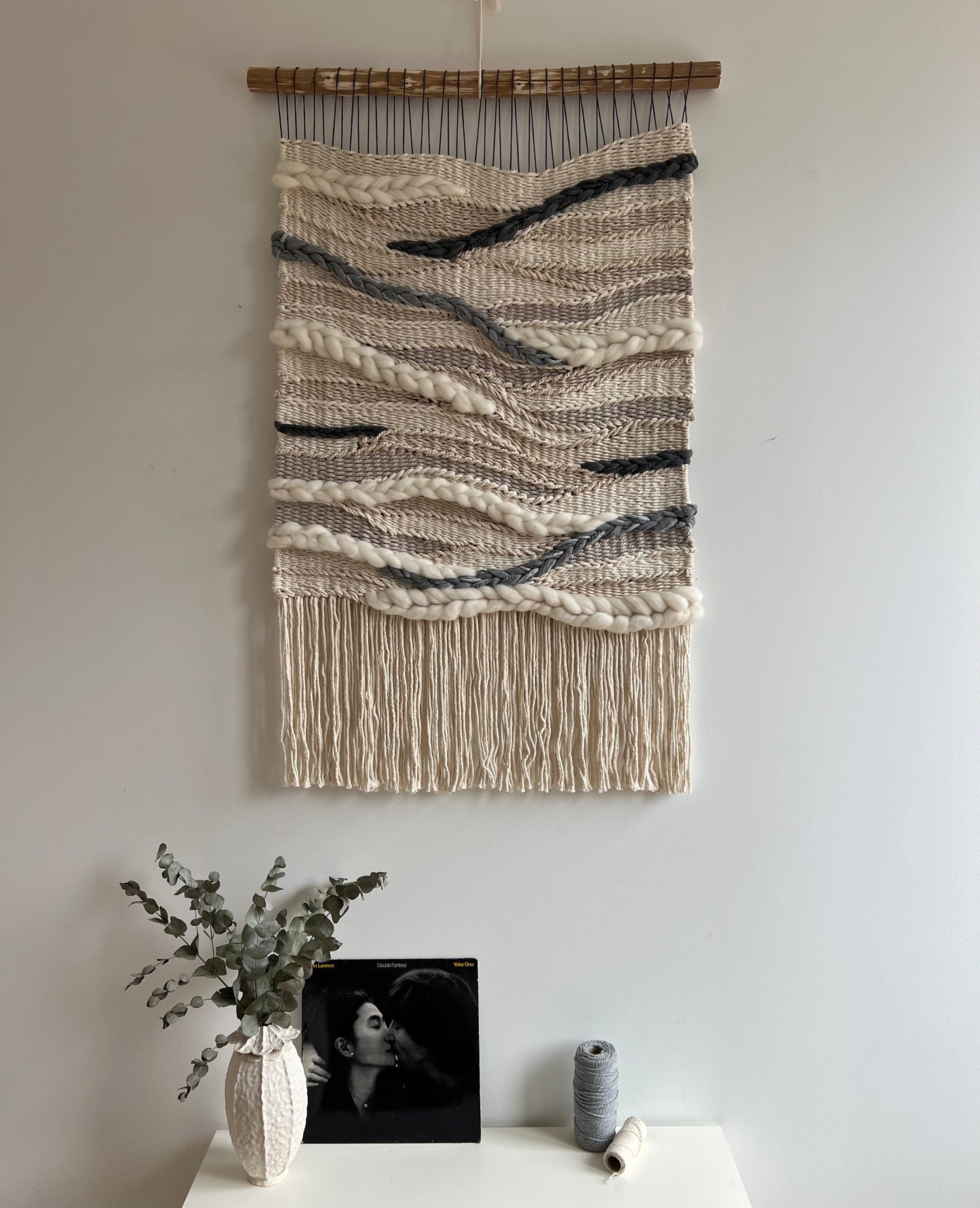 Long woven wall tapestry styled above a console table with decor