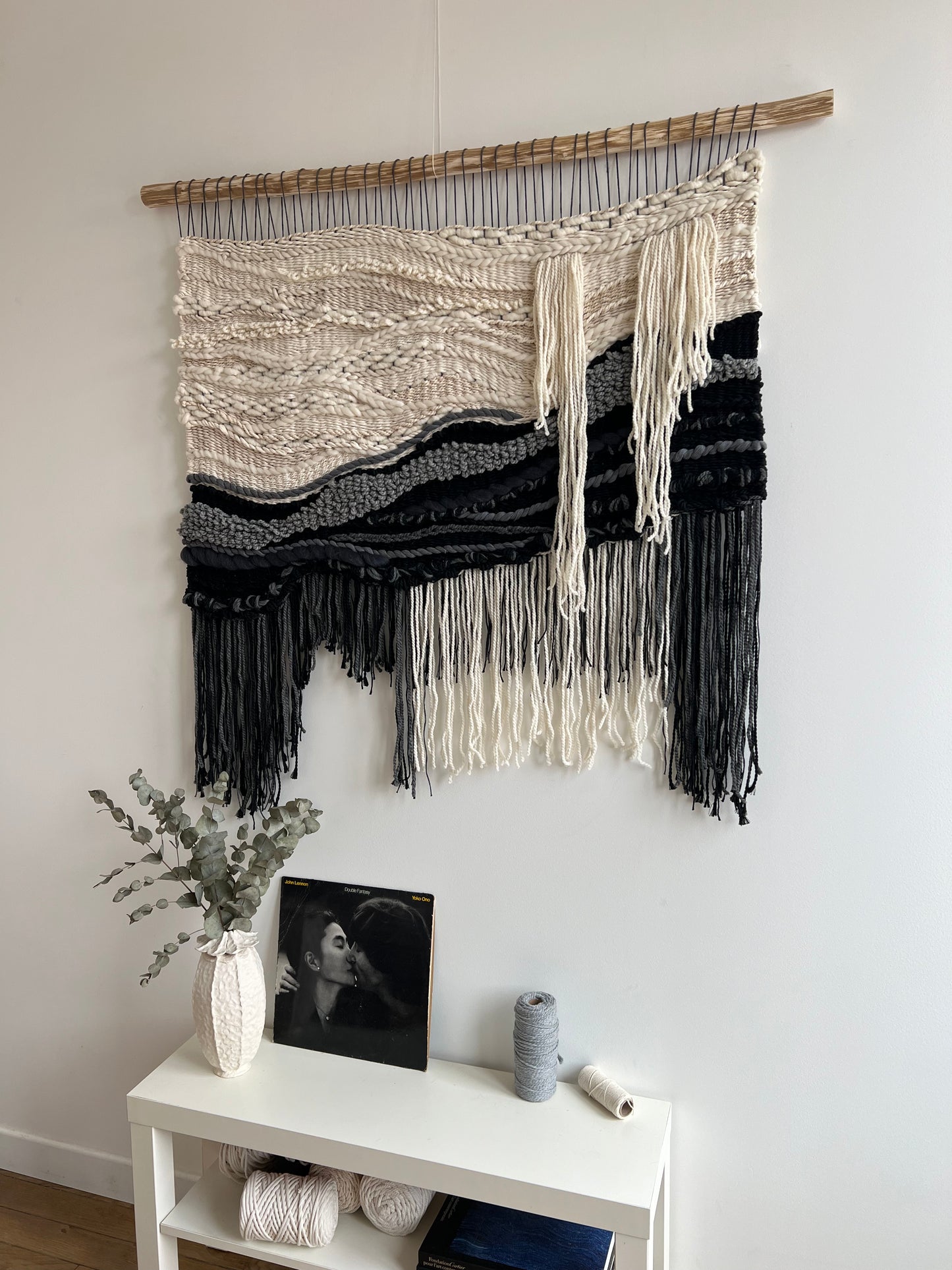 Side angle view of monochrome woven wall hanging showing layered yarn textures
