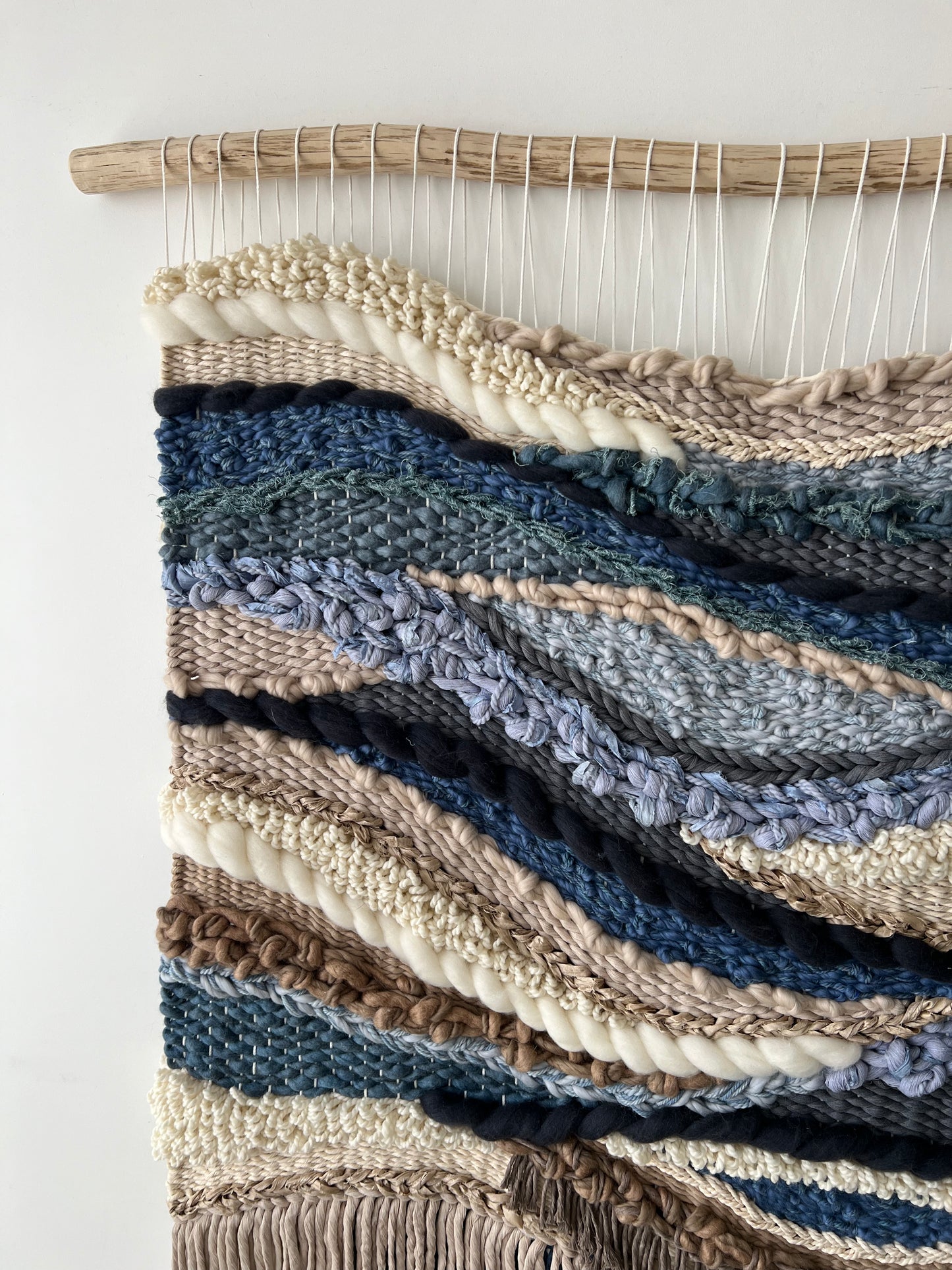 Macro view of woven textile art highlighting yarn thickness, layered weaving, and natural boho aesthetic