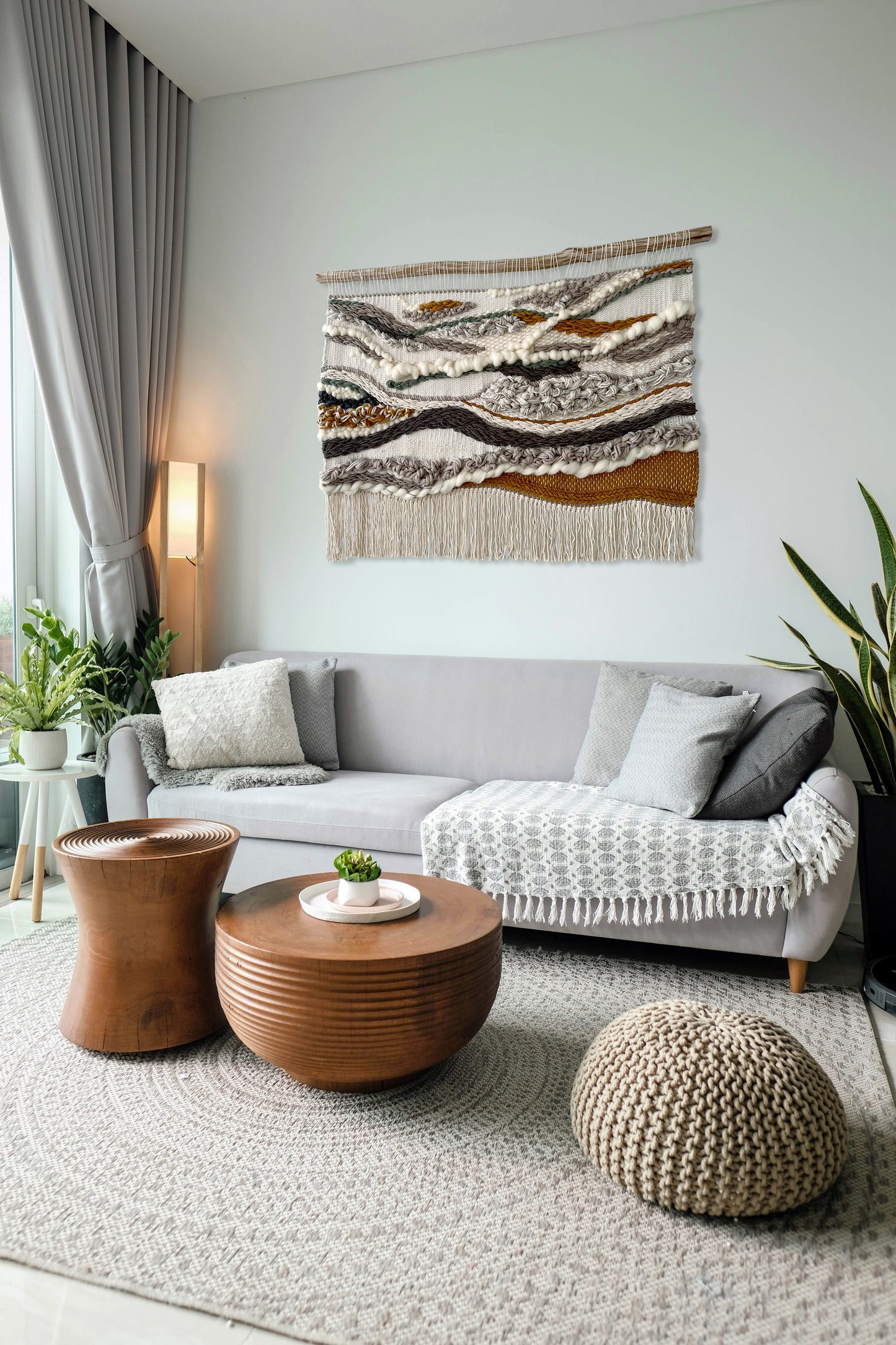 Boho living room with large handwoven wall tapestry in beige, mustard and natural tones