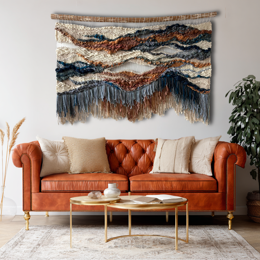 Handwoven textile wall art in terracotta and blue tones displayed above a sofa in a modern living room interior