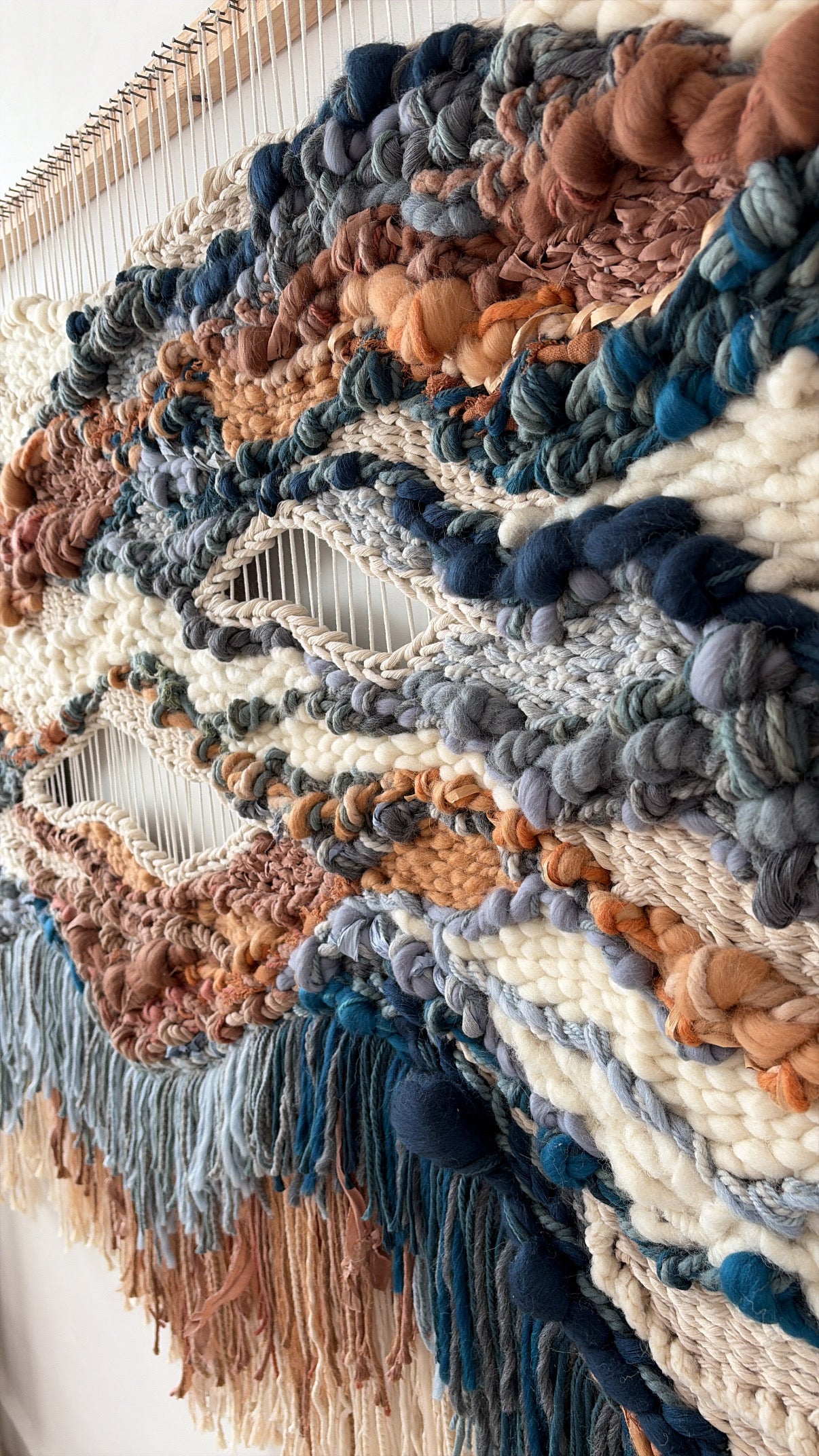 Side view of the textile wall hanging revealing layered construction and rich variation in woven textures and depth