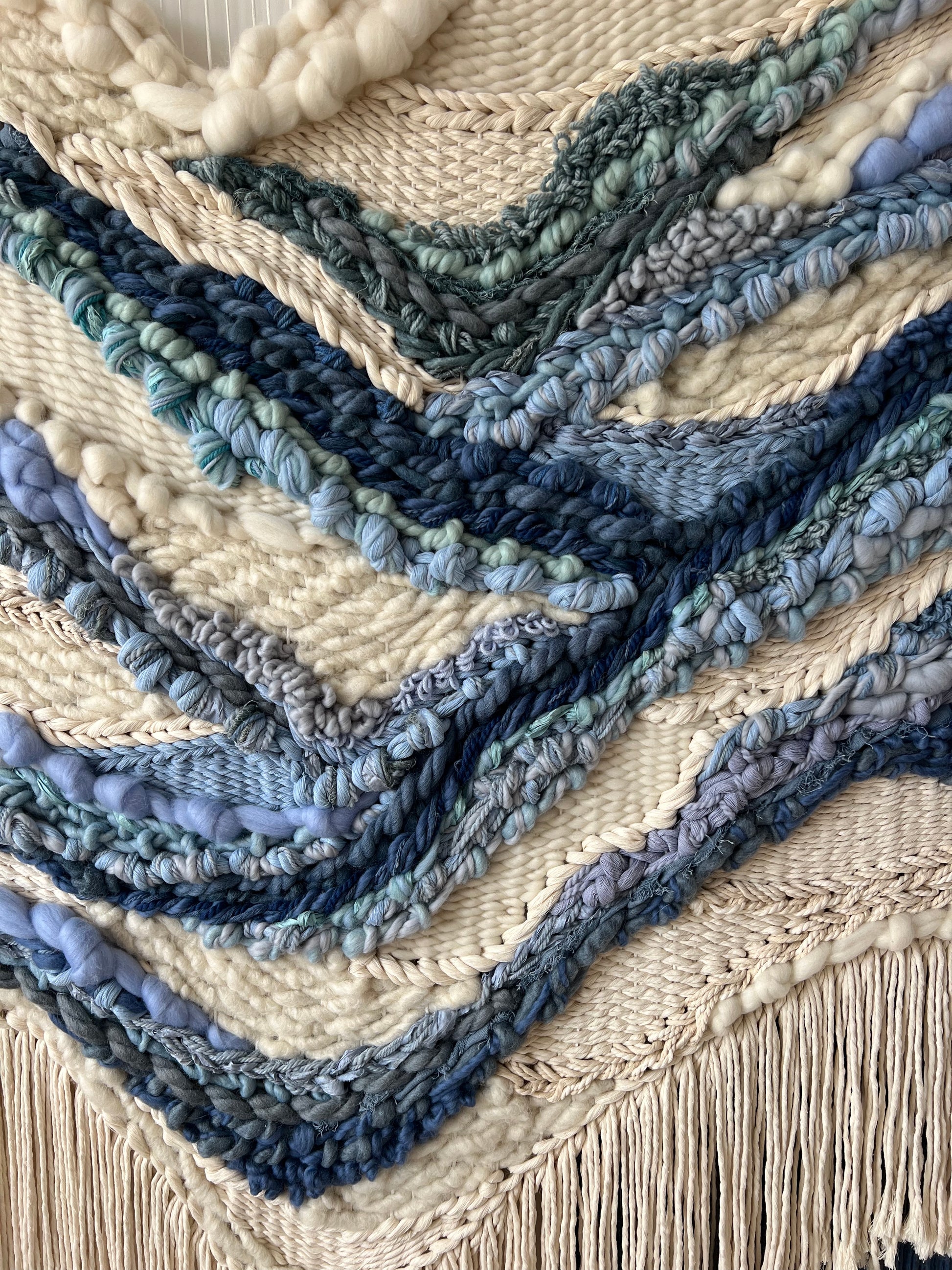 Detailed texture of cream wool tapestry with bold blue river motif