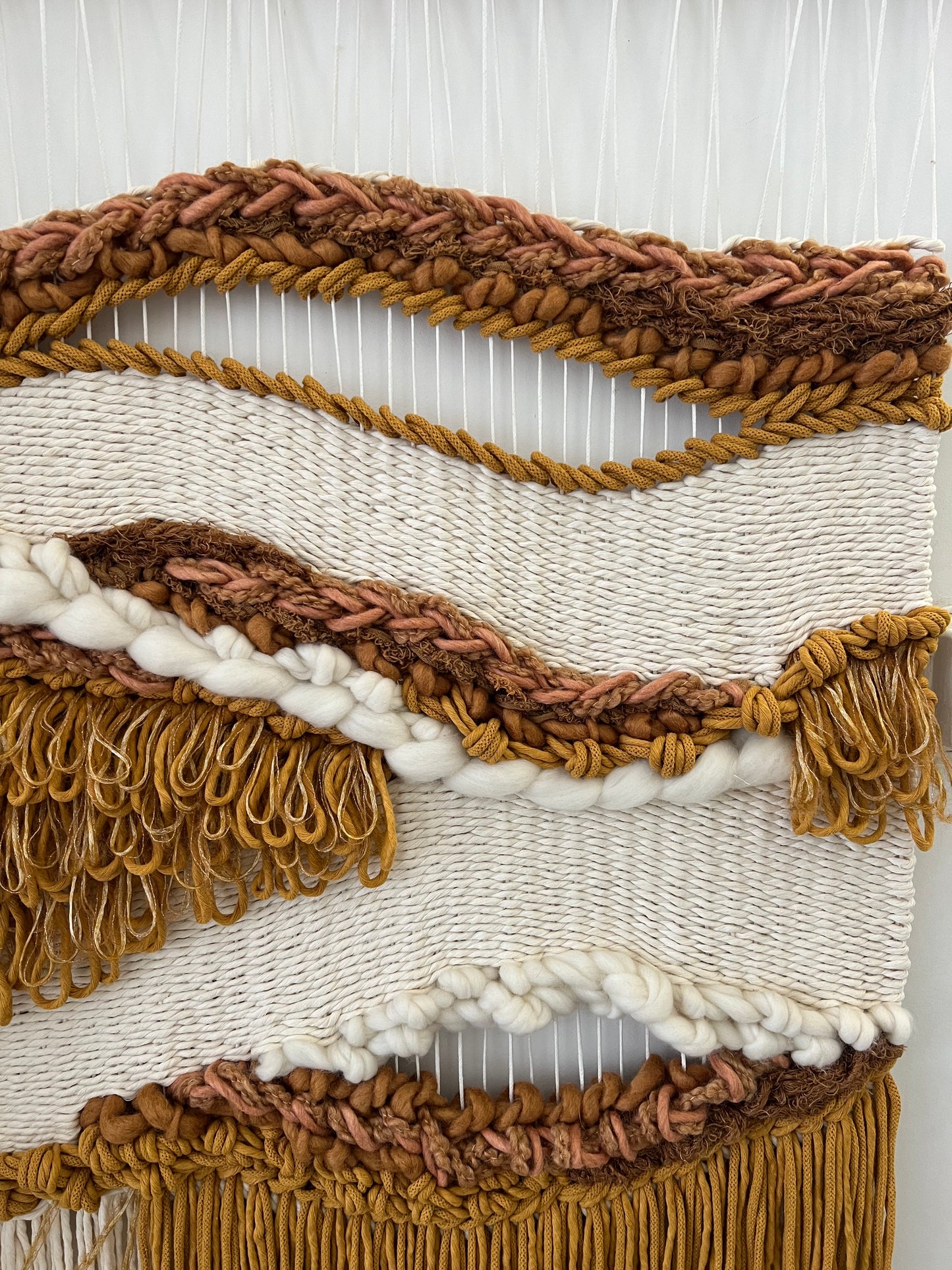 Close-up of woven textures in earthy mustard and cream yarn with braided details