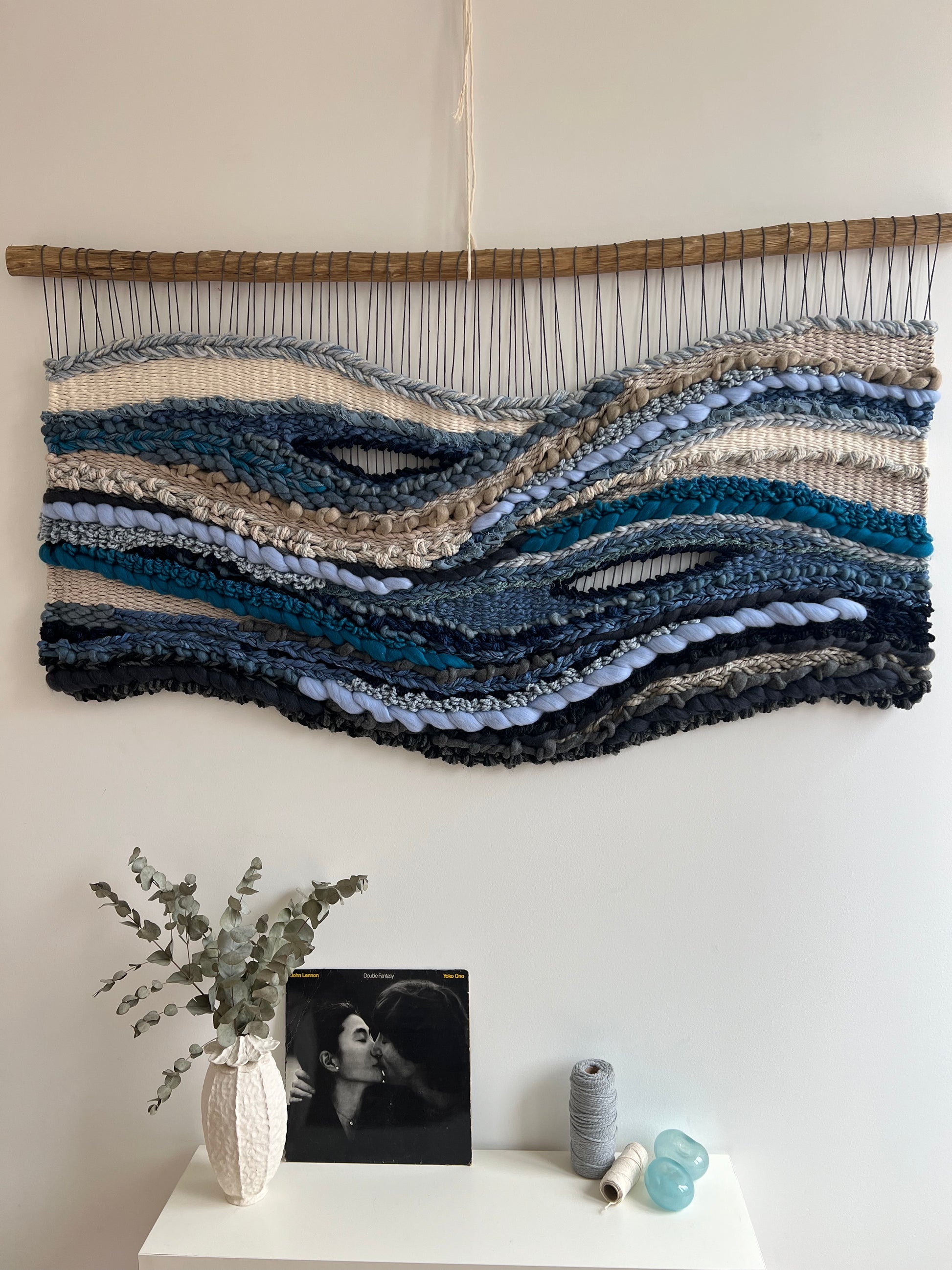 Artistic close-up of woven fiber art 'Breath of the Ocean', showing organic textures in blue, grey and cream yarns