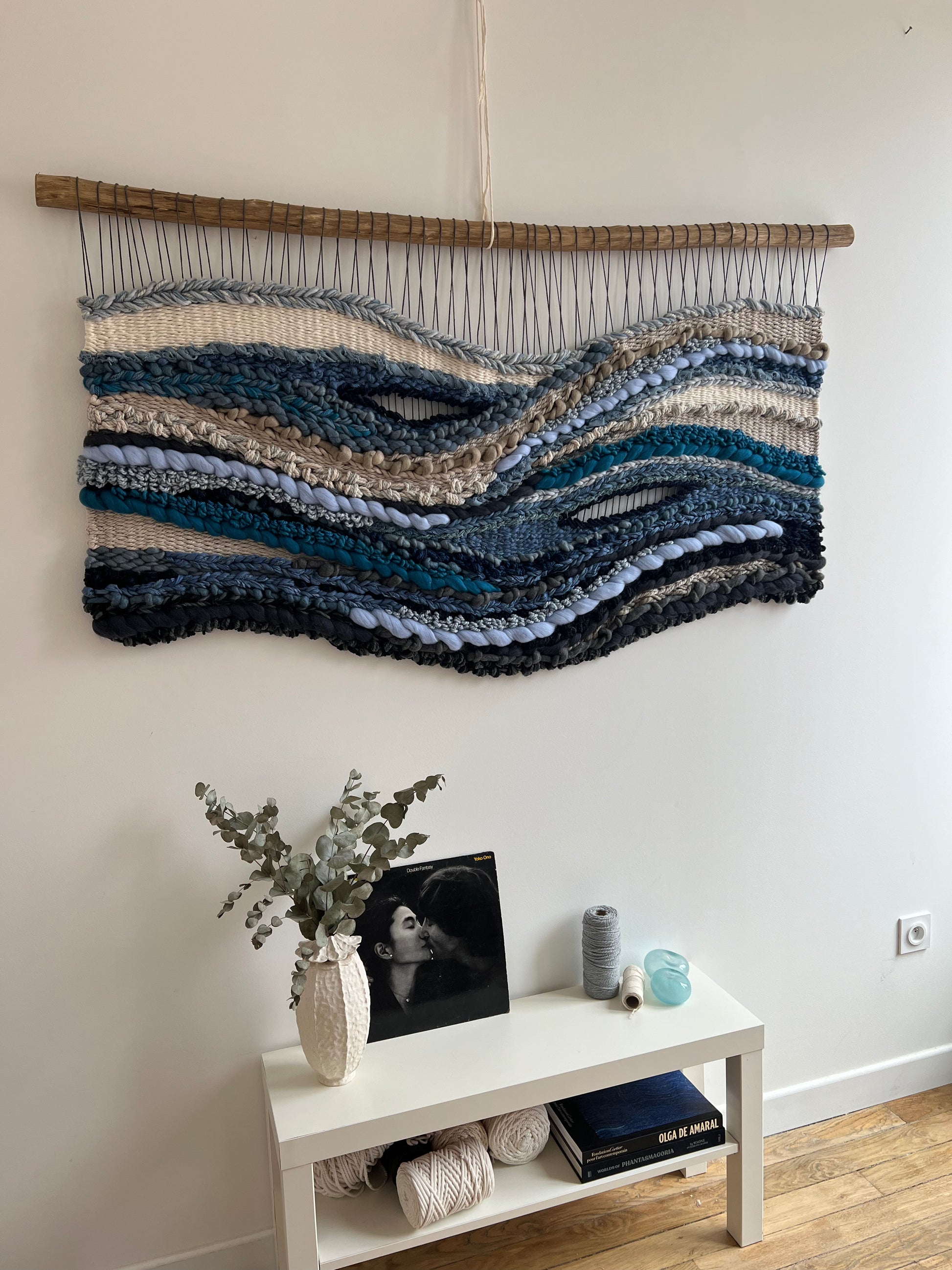 Side view of woven wall hanging, showing layered textures and wave-like blue patterns