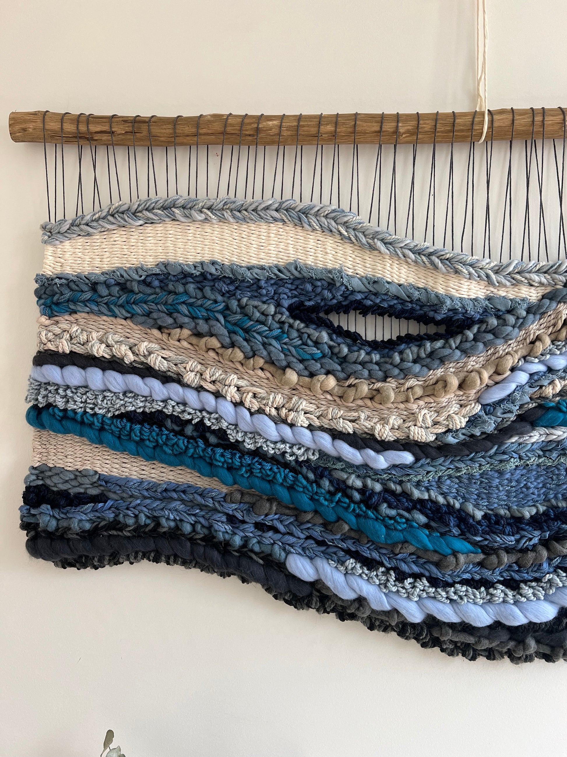 Close-up of woven wall art showing intricate blue and grey wave textures