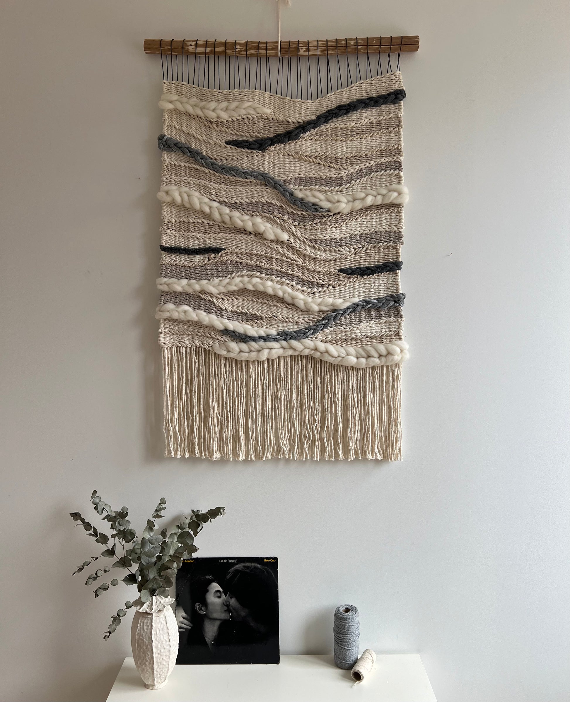 Long woven wall tapestry styled above a console table with decor