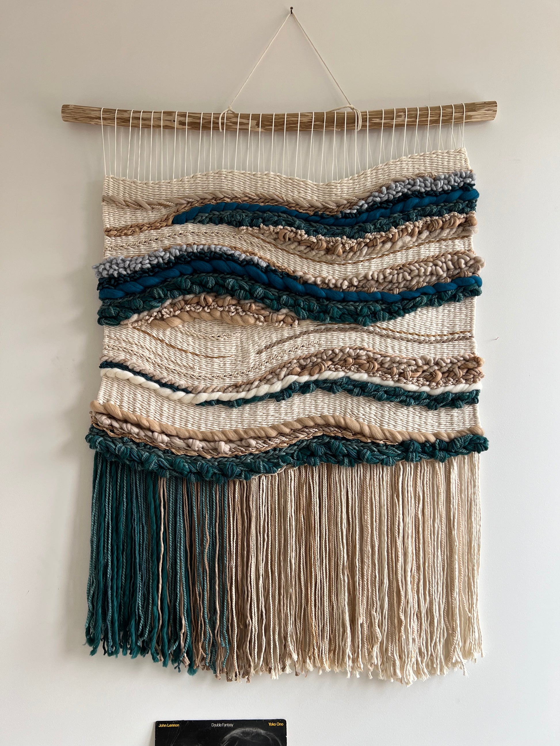 Coastal handwoven wall tapestry with gradient fringe displayed on a minimalist white wall