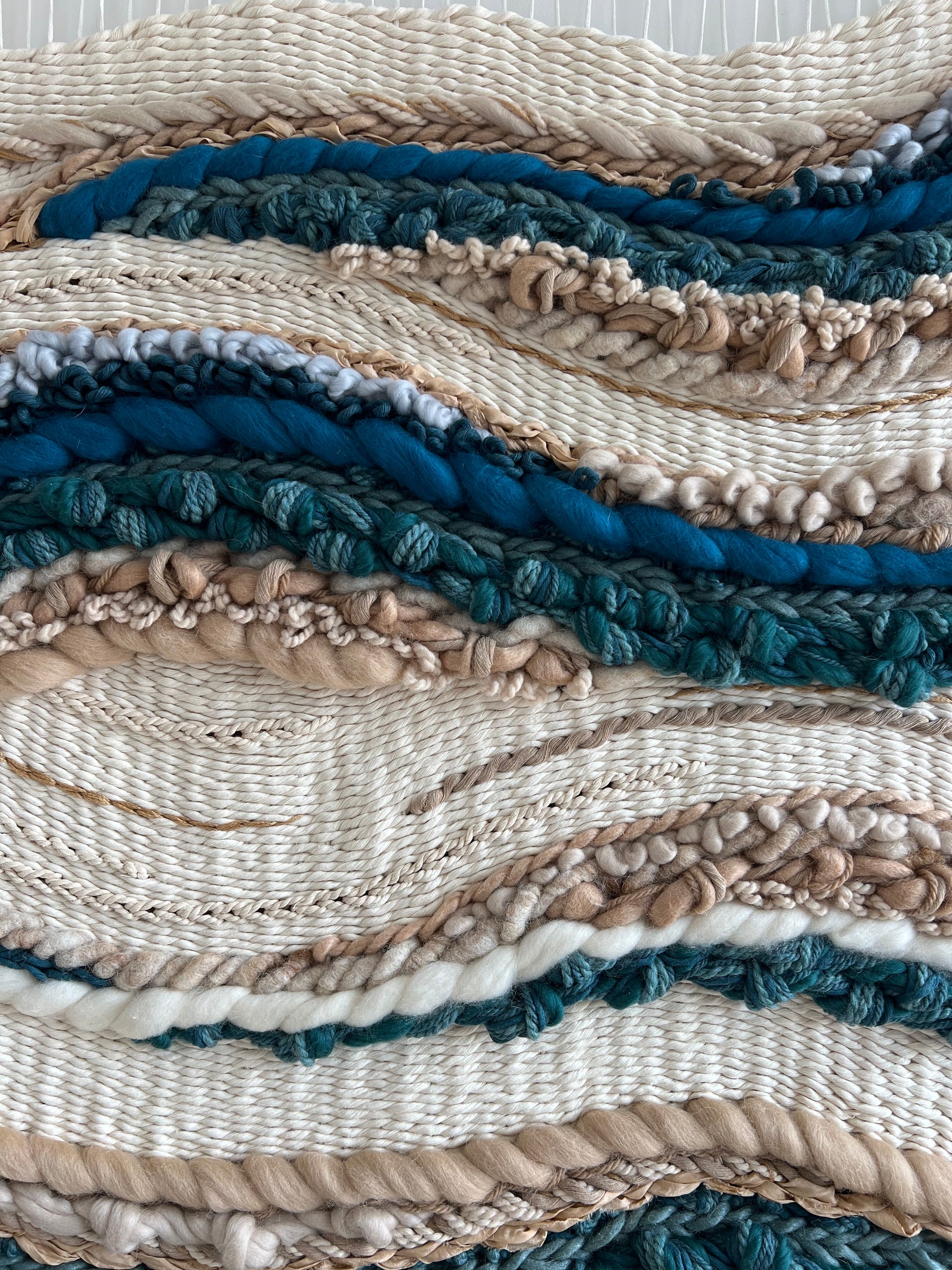 Close-up of textured weaving in blue and beige tones on ocean inspired wall tapestry