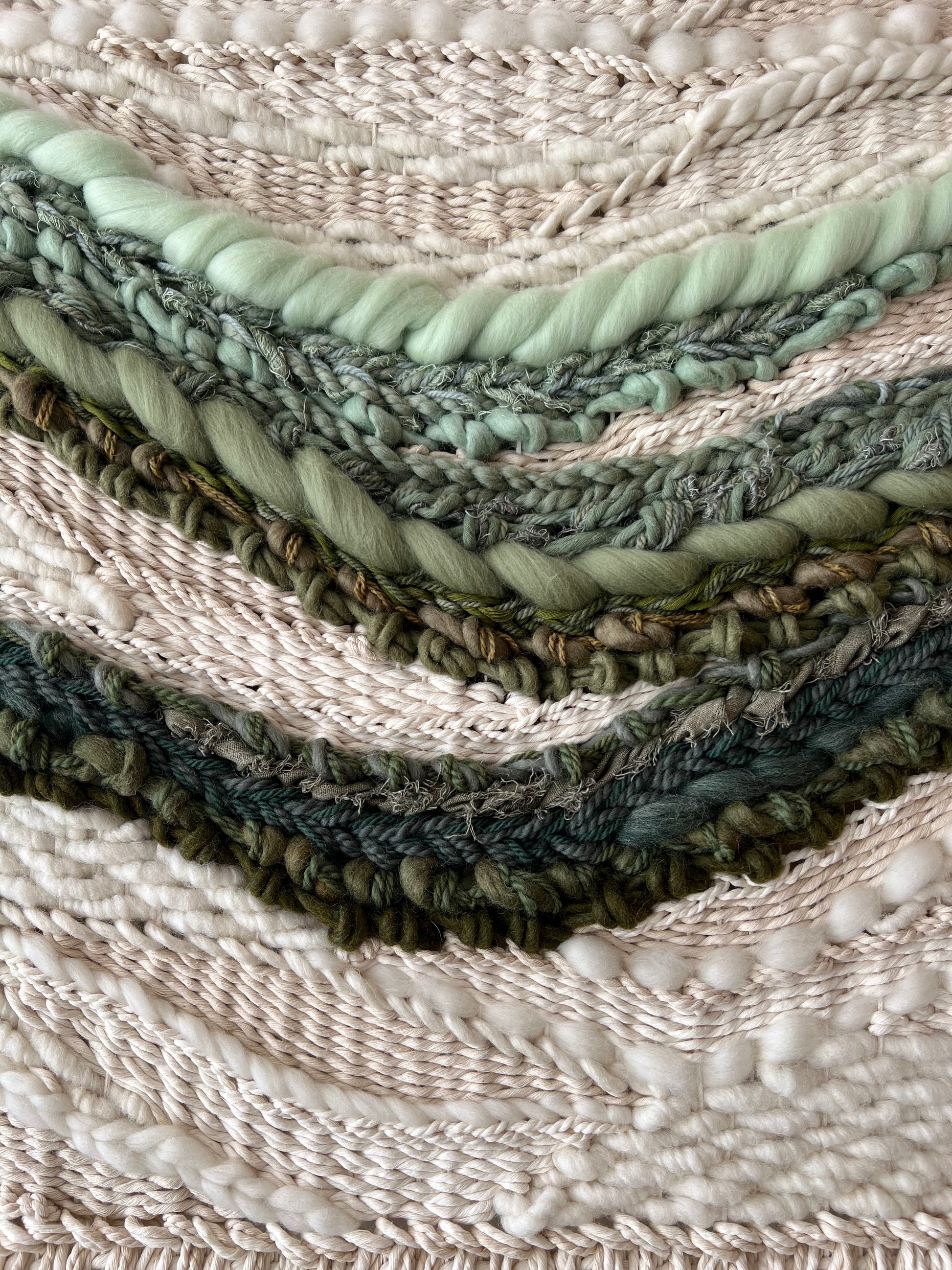 Macro shot of woven fiber art, highlighting green wave pattern and thick textured weave