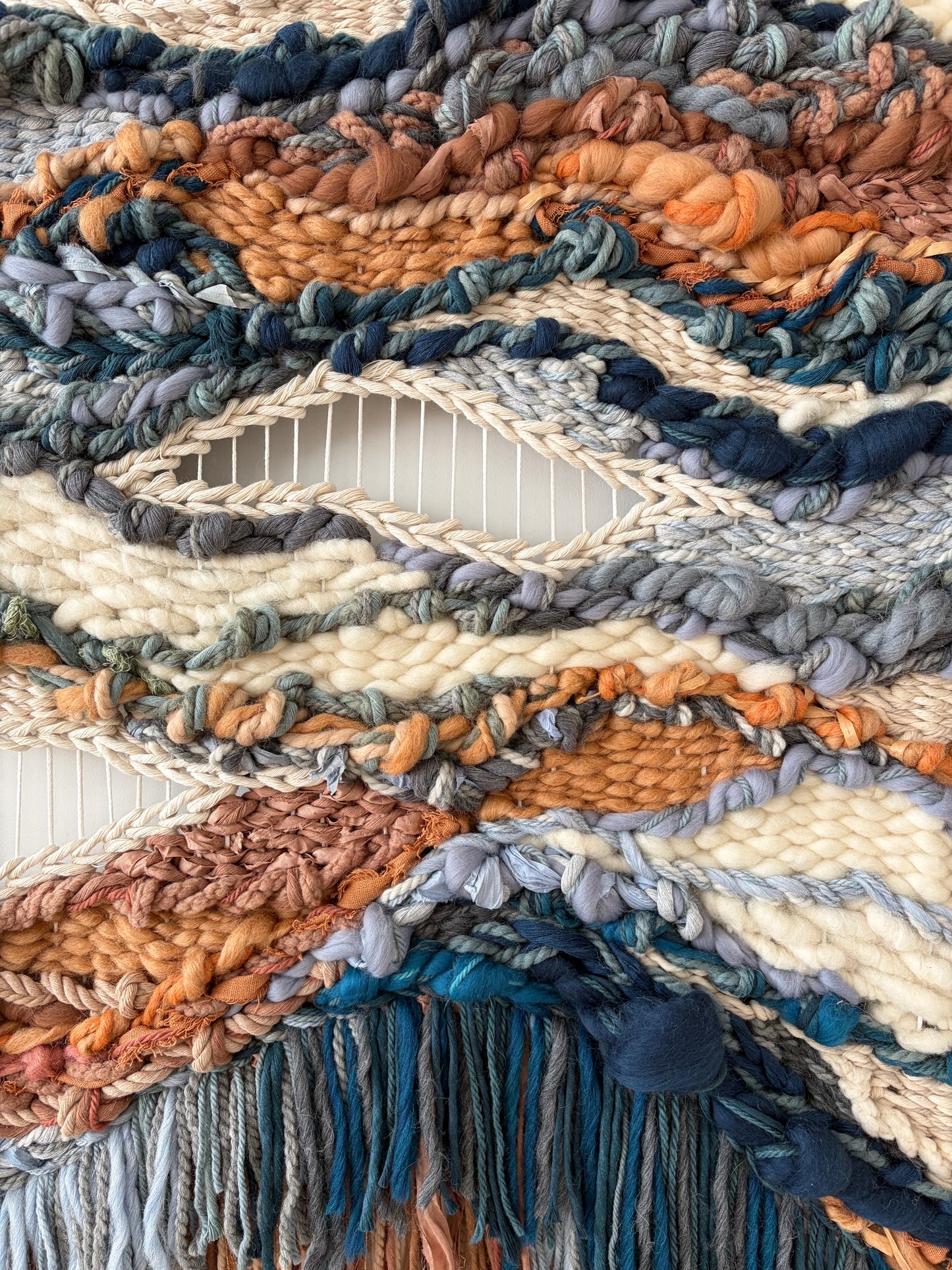 Macro view of sculptural fiber art highlighting raised weaving patterns and tactile textile structure.