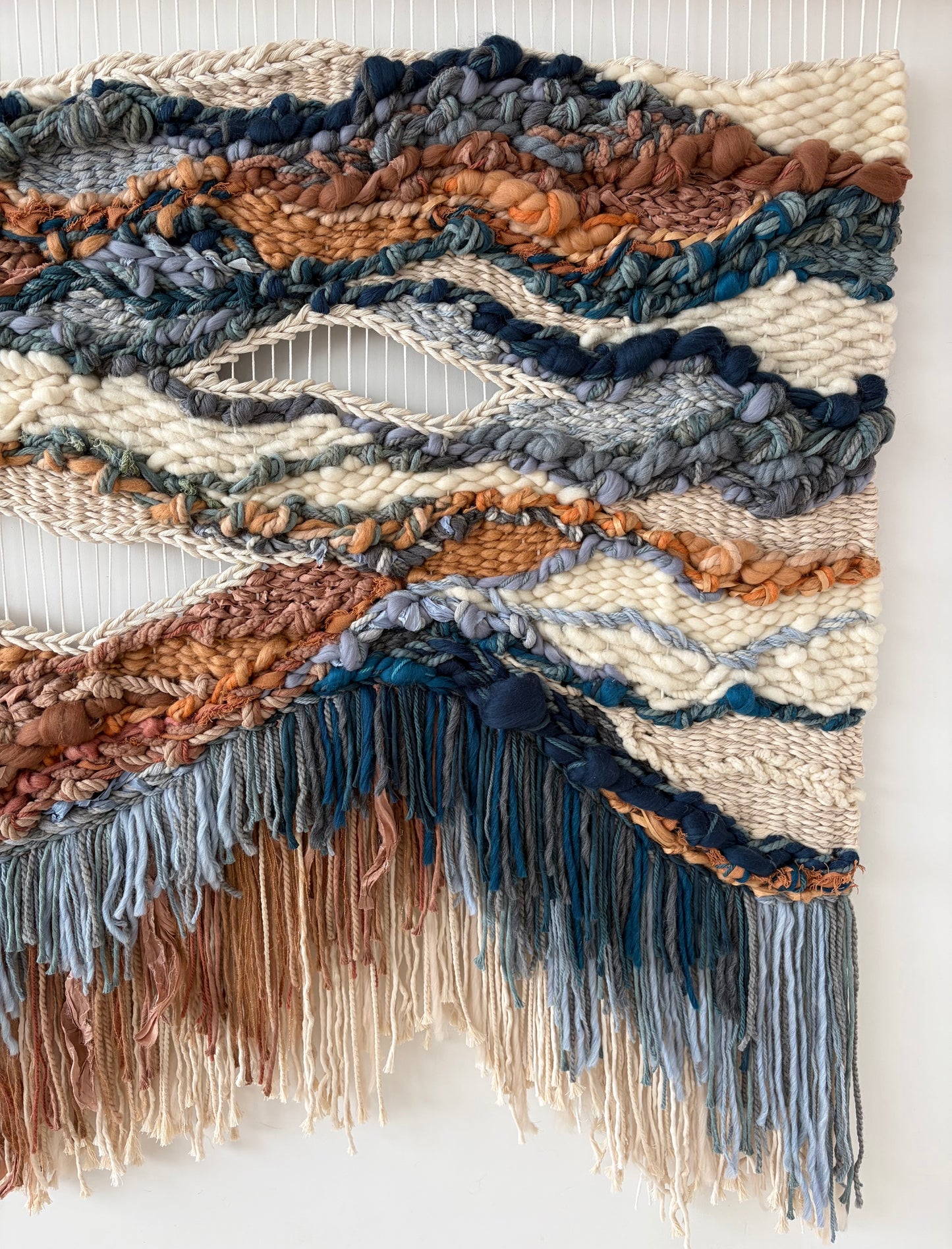 Detail of asymmetric fringe and hand-knotted fibers creating movement and organic texture.