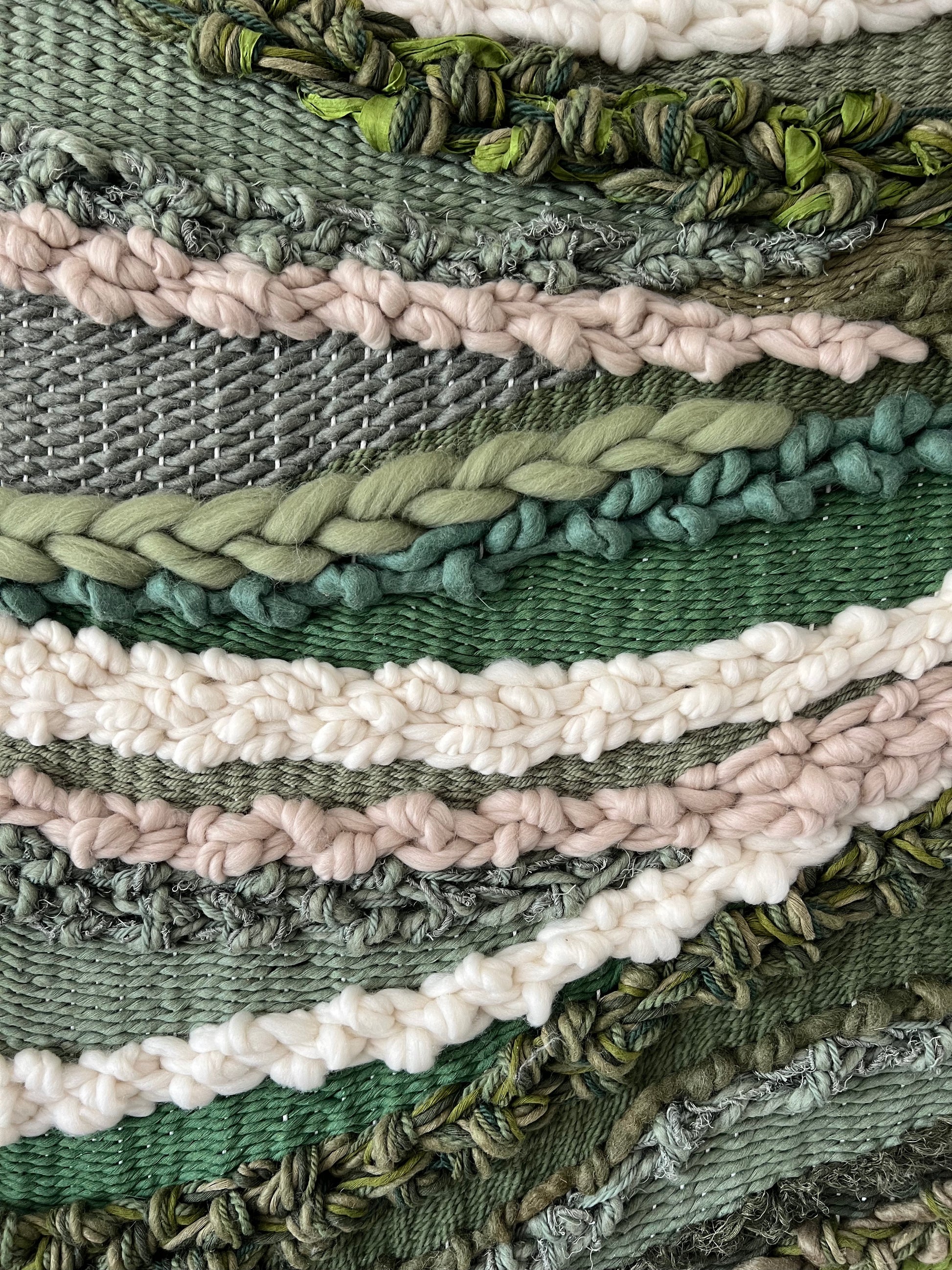 Detail of thick green cotton and wool yarns interlaced in the textile wall art