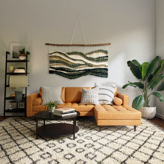 Handwoven wall hanging in green and cream tones displayed above a modern sofa