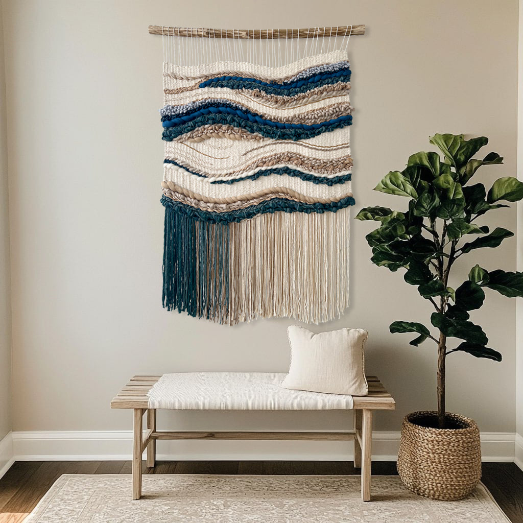Handwoven ocean and sand inspired wall tapestry above entryway bench with blanket and plant